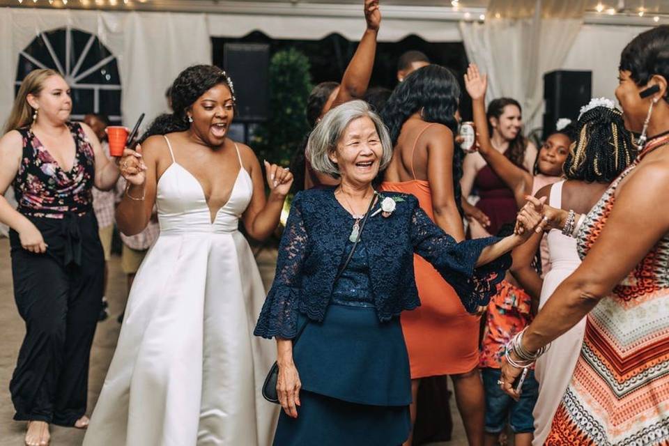 mothers of the bride and groom laugh while dancing together during reception