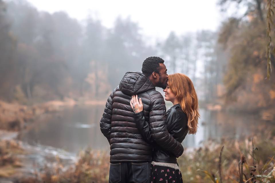 man in a winter coat kissing woman on forehead