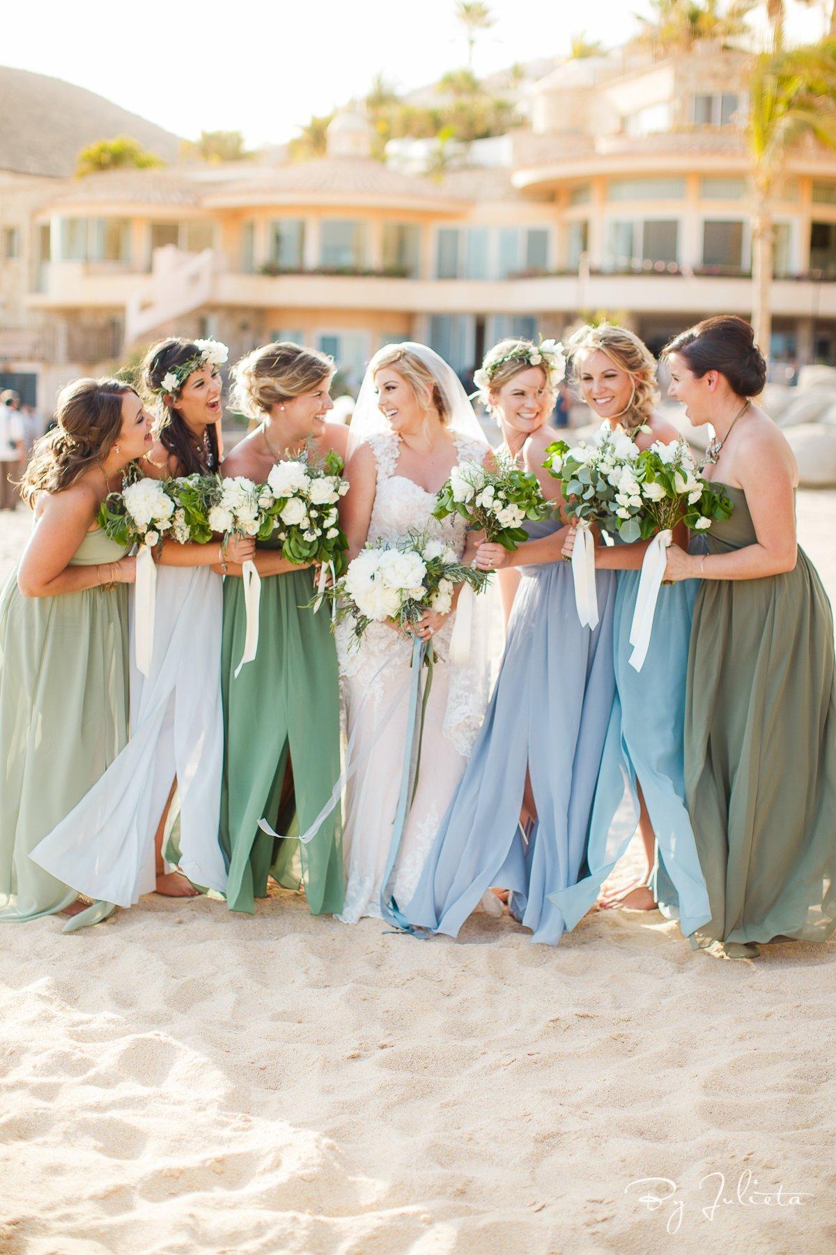 Bridesmaids surrounding bride and wearing pastel hues of green, purple, and blue