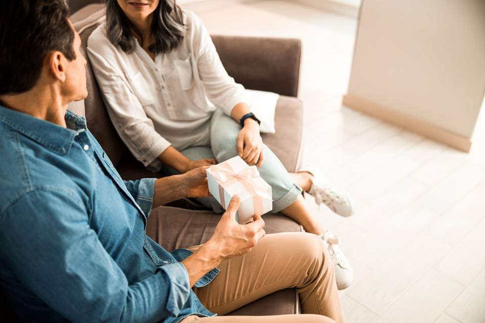 couple exchanging gifts while sitting on couch