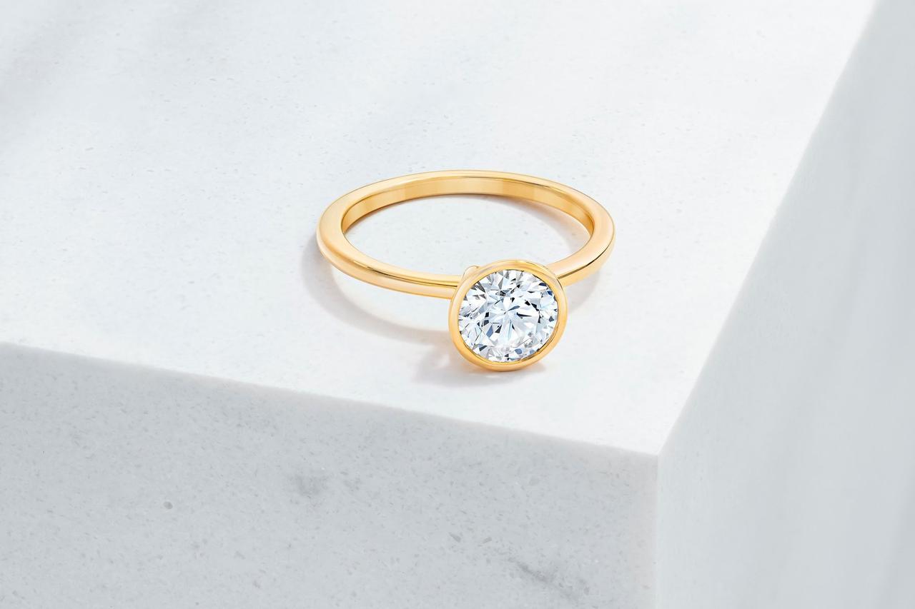 Round-cut diamond bezel-set engagement ring with yellow gold band