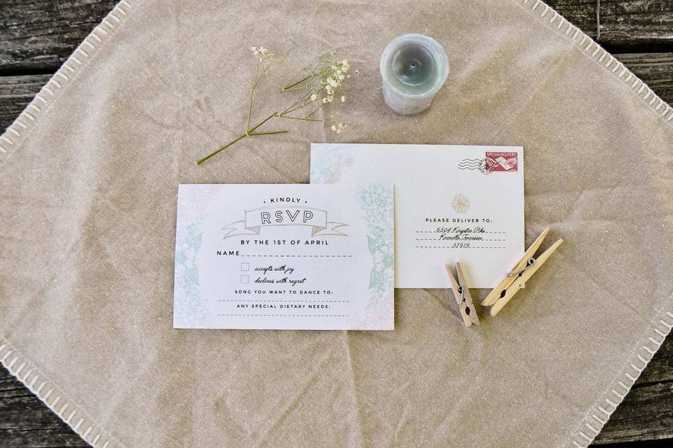 rustic wedding rsvp card placed on a scrap of burlap surrounded by baby's breath, clothespins, and twine