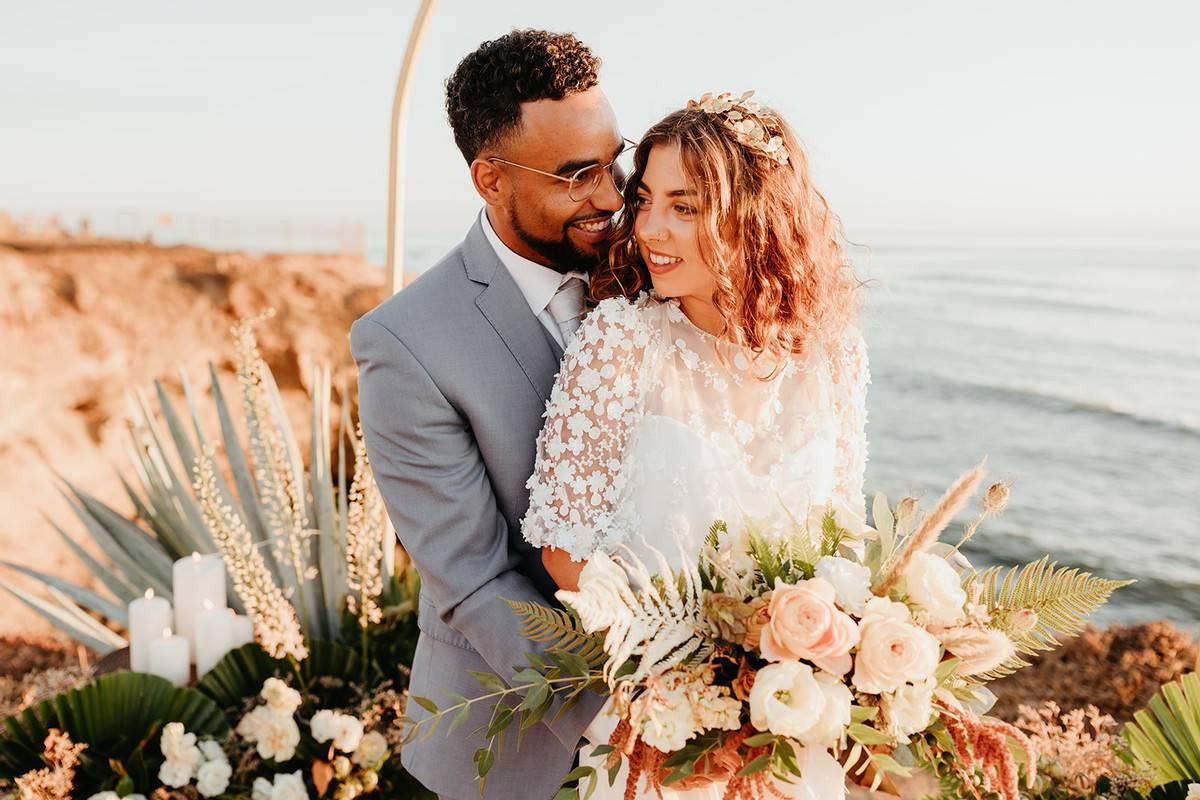 Bride holds rose and dried greenery summer wedding bouquet