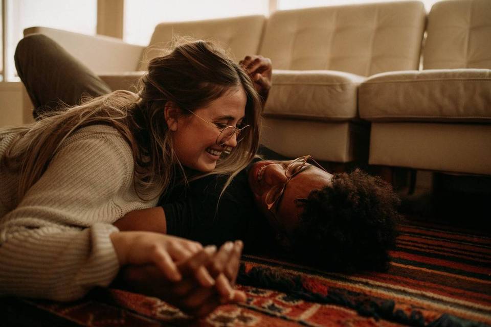 couple laying on floor smiling laughing holding hands