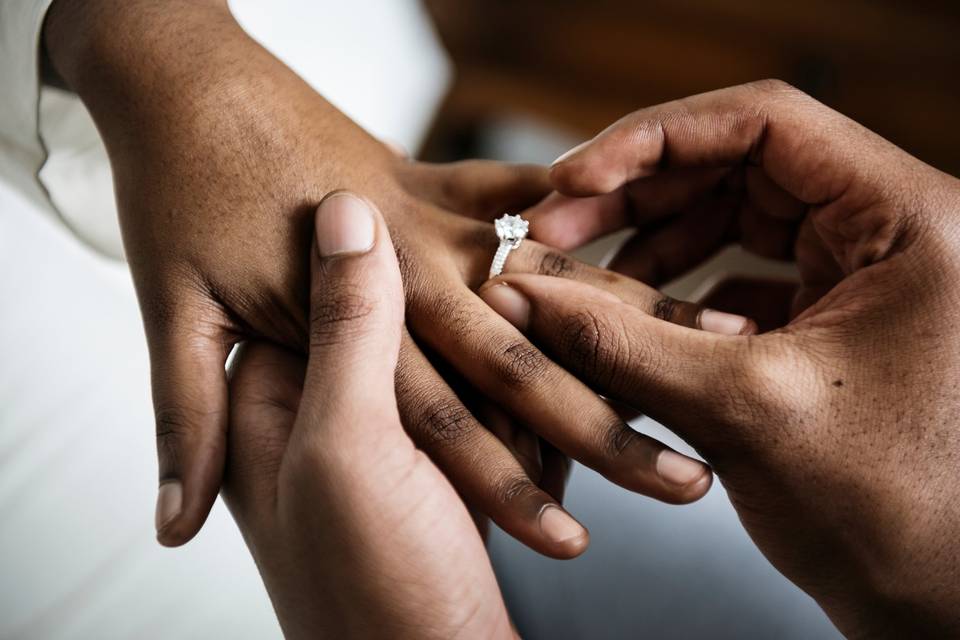 close-up of man placing engagement ring on woman's finger