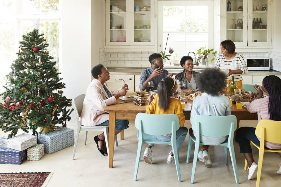 family eating dinner next to a christmas tree
