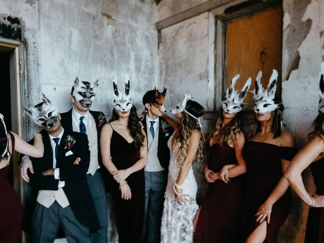 bride and groom stand with their wedding party wearing woodland creature masks