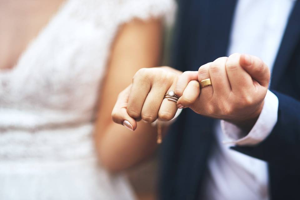 bride and groom with locked pinkies wearing wedding rings