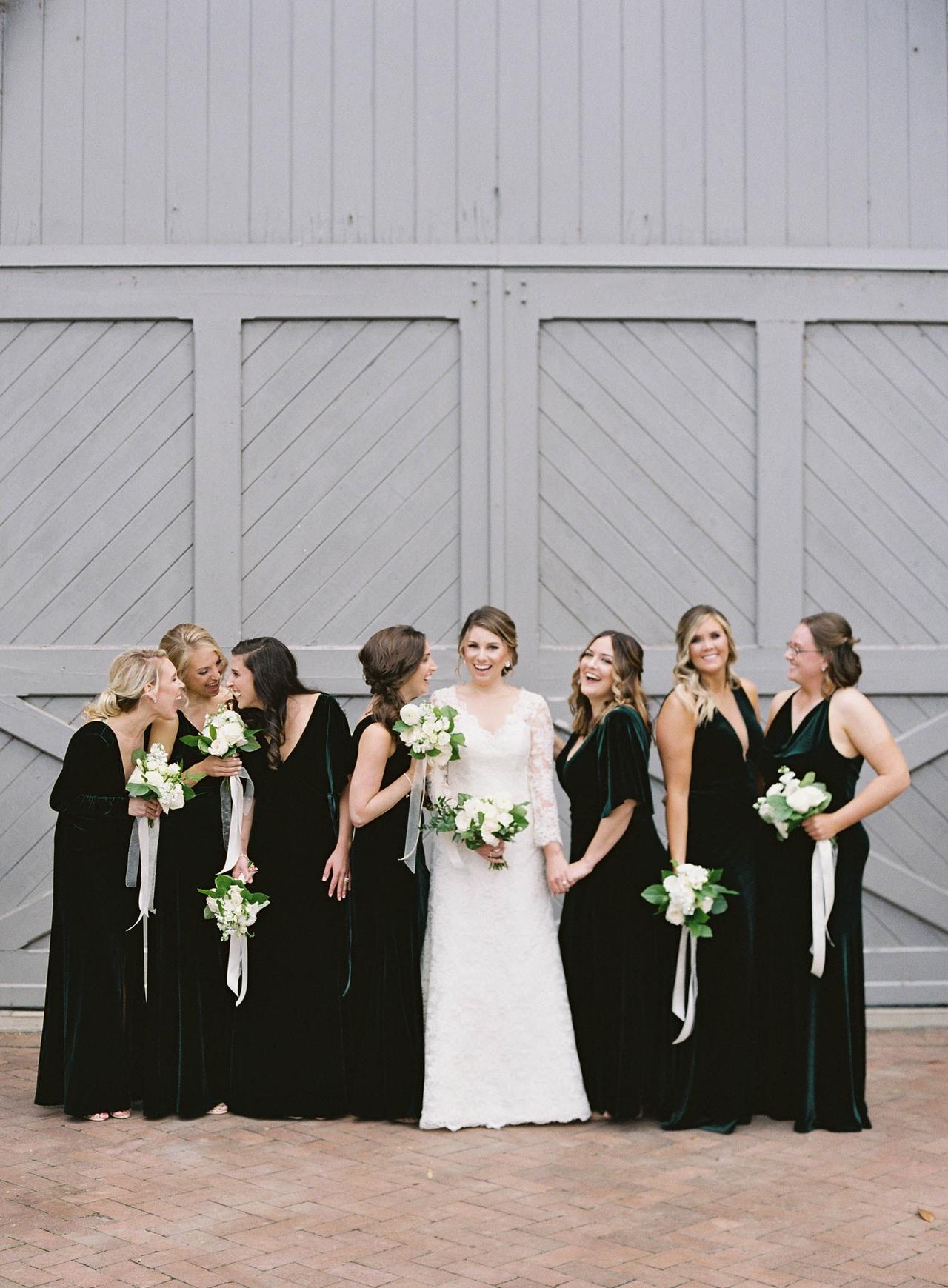 Bride posing with bridesmaids in deep green velvet dresses
