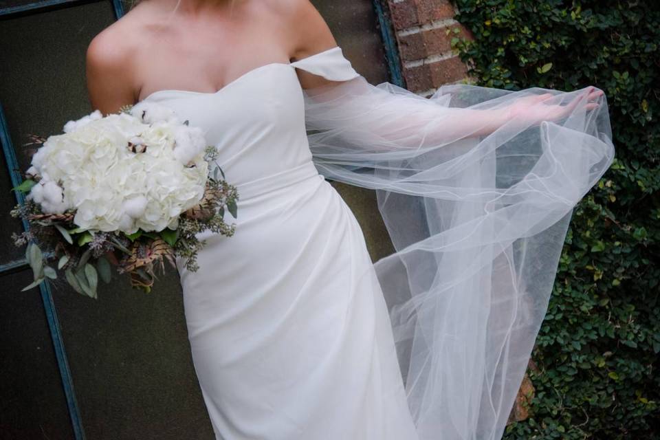 bride wearing a long white veil and carrying a white bouquet