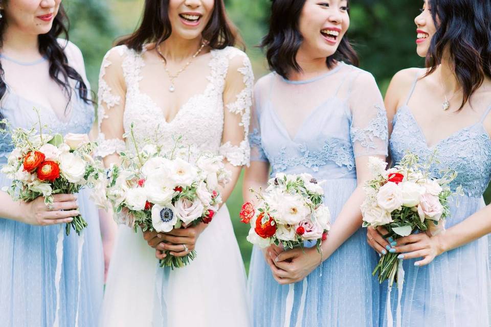 bride and bridesmaids in light blue dresses carrying white and red bouquets