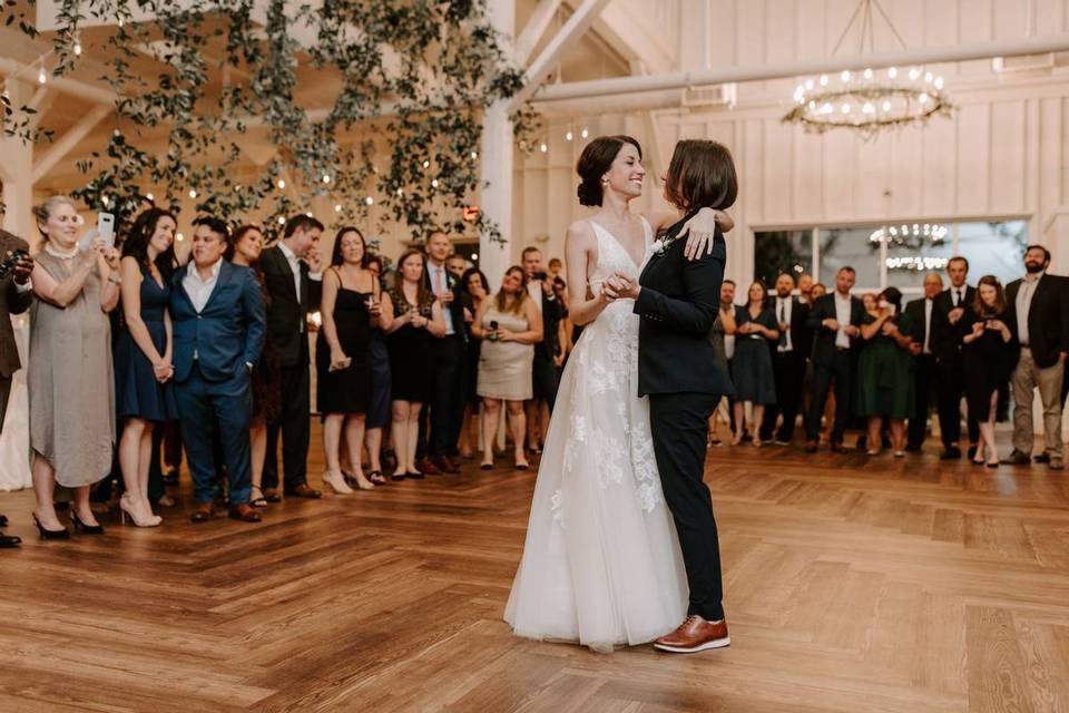 same sex couple performing first dance surrounded by guests