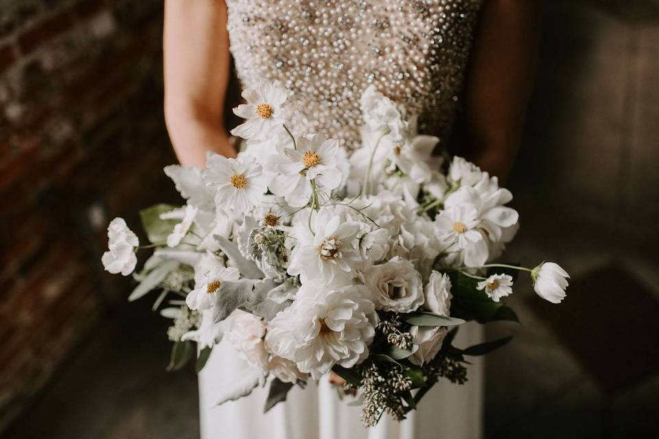 bride holding all white wedding bouquet of tulips, lisianthus and greenery