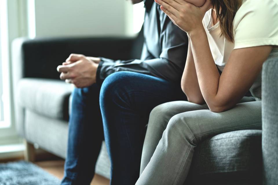 woman and man sitting next to each other looking upset