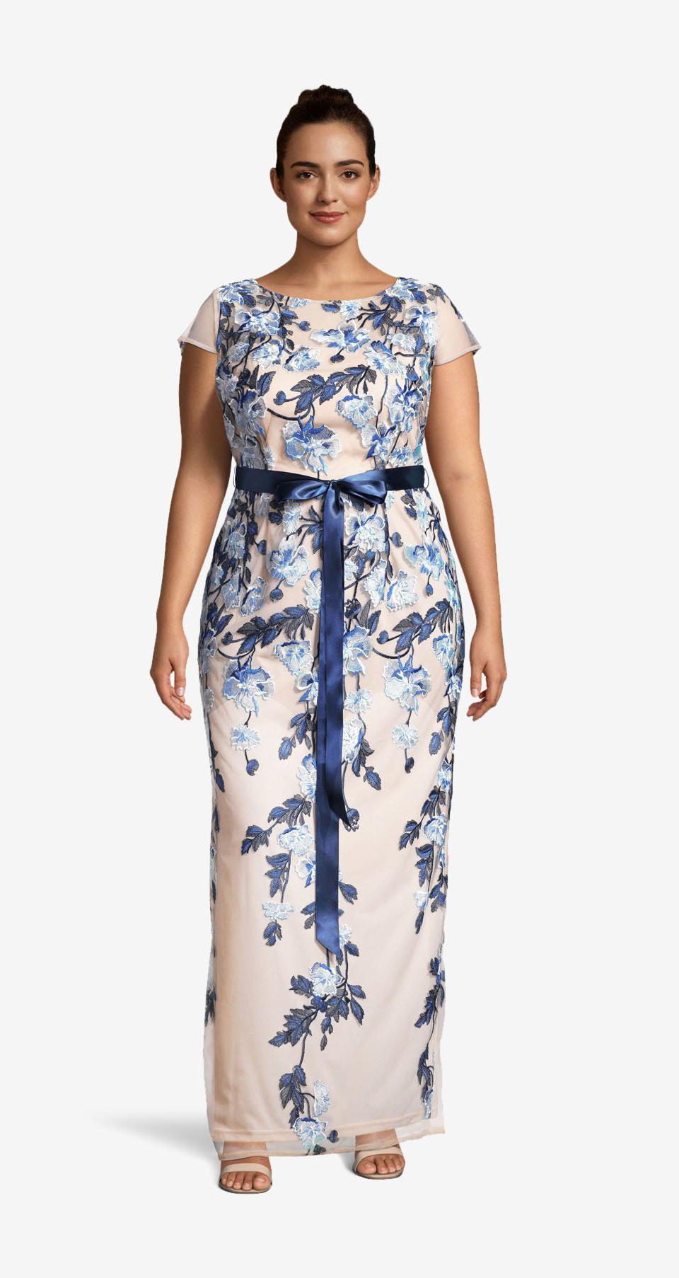 Model wearing nude column floor-length gown with beautiful light and dark blue floral pattern, sheer capped sleeves and blue ribbon around the waist