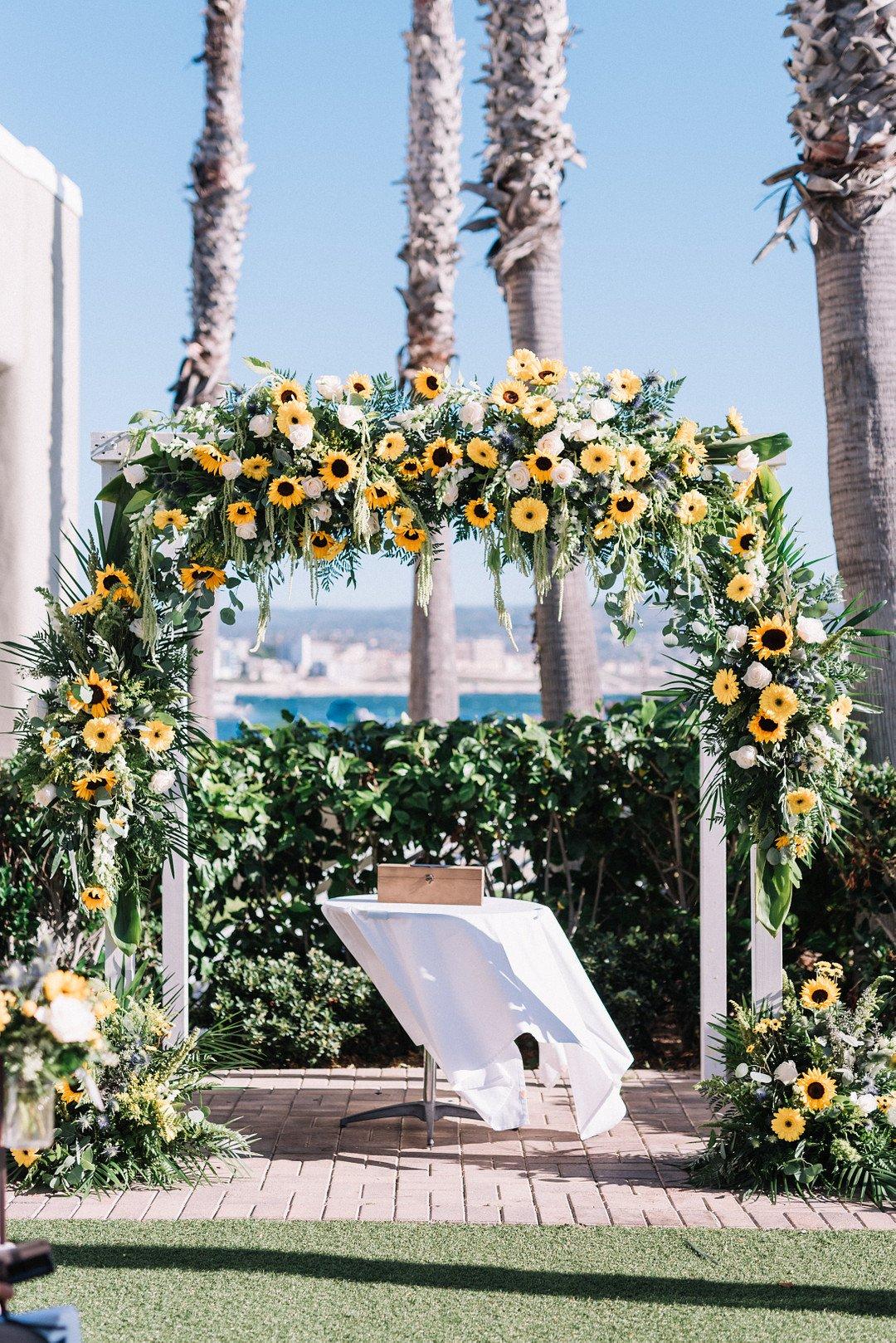 sunflower wedding ceremony arch with yellow gerbera daisies, white roses and greenery