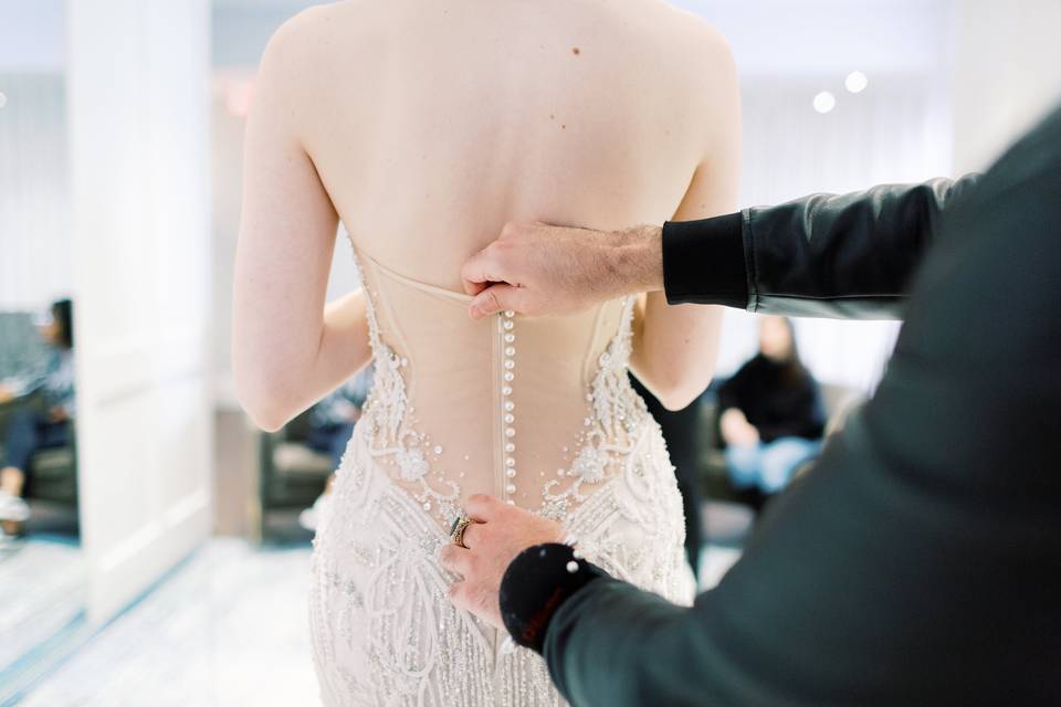 bride trying on wedding dress with buttons down back