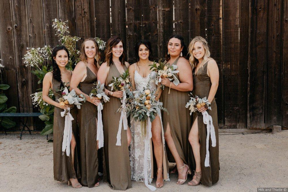 Bridesmaids wearing green dresses with brown undertones in photo with bride