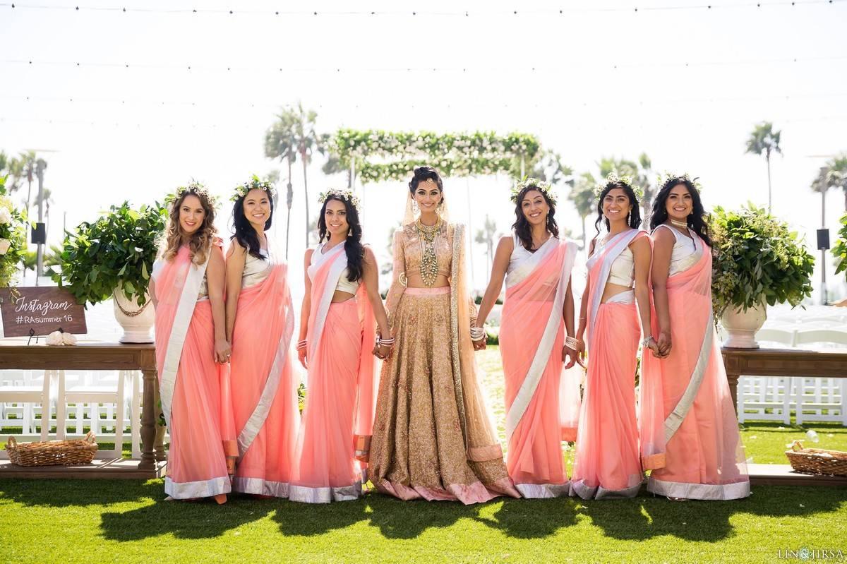 Bride and bridesmaids holding hands for photo op outside with bridesmaids wearing coral