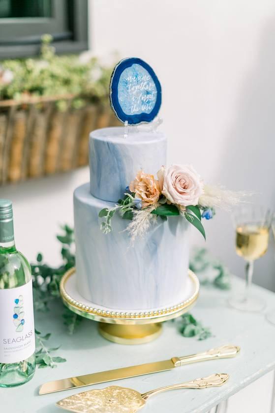 blue wedding cake decorated with marbled pattern and fresh flowers