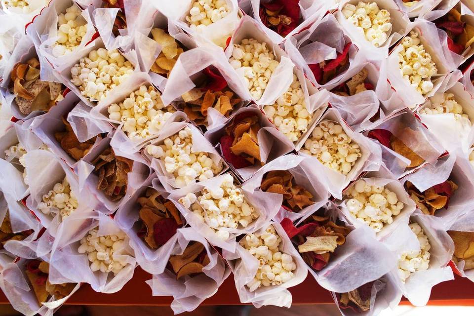 individual paper cartons of popcorn and tortilla chips are lined in rows on a table 