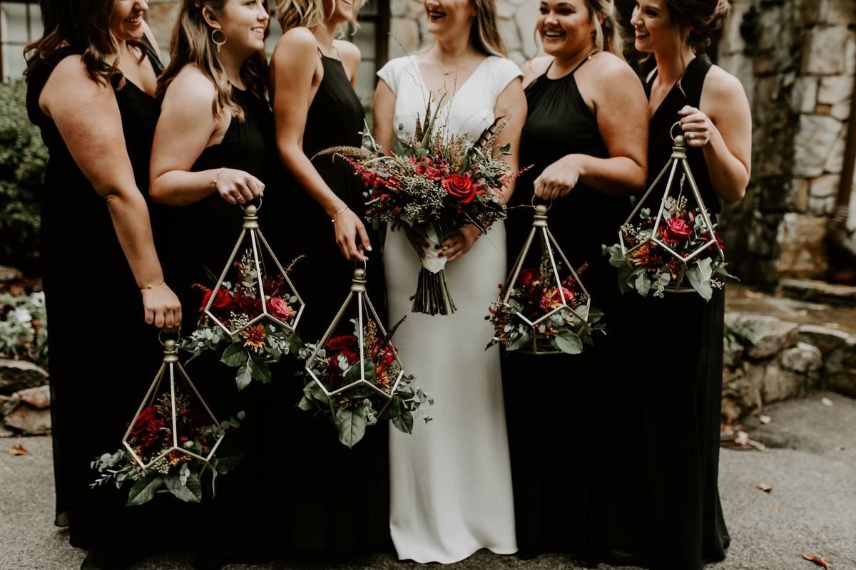 bridesmaids stand next to bride holding geometric lanterns filled with flowers as bouquets