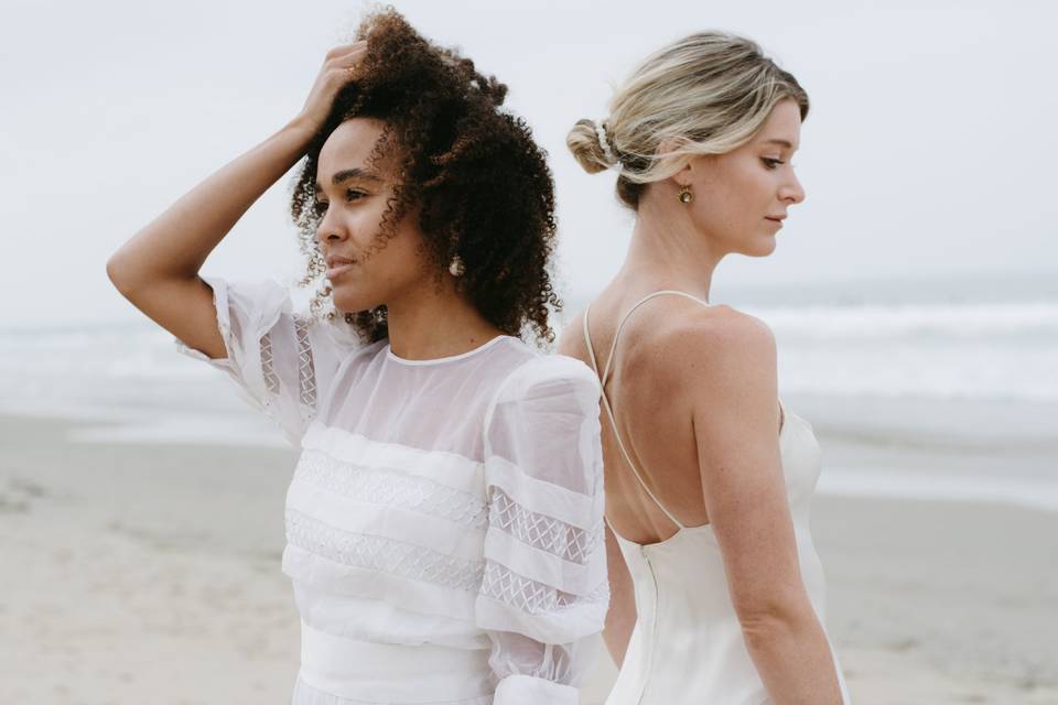 Two models on a beach wearing upcycled vintage wedding dresses