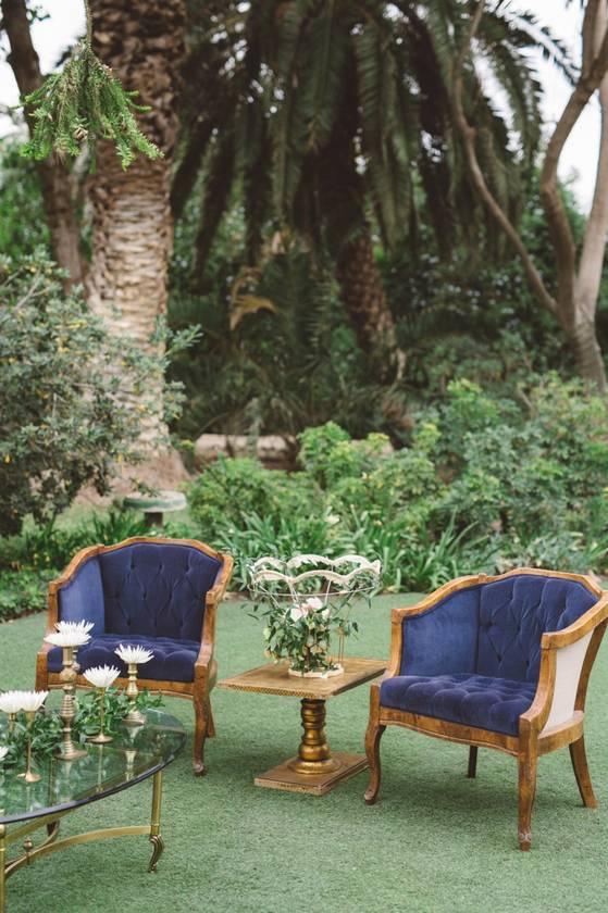 two upholstered arm chairs with navy blue velvet fabric at outdoor wedding lounge area