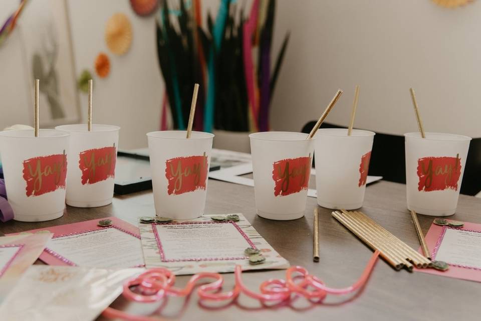 plastic cups with reusable straws sit on a table surrounded by board games