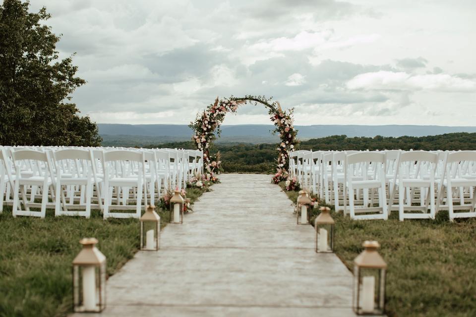 outdoor wedding aisle decor with white pillar candles in glass and wooden lanterns along the aisle