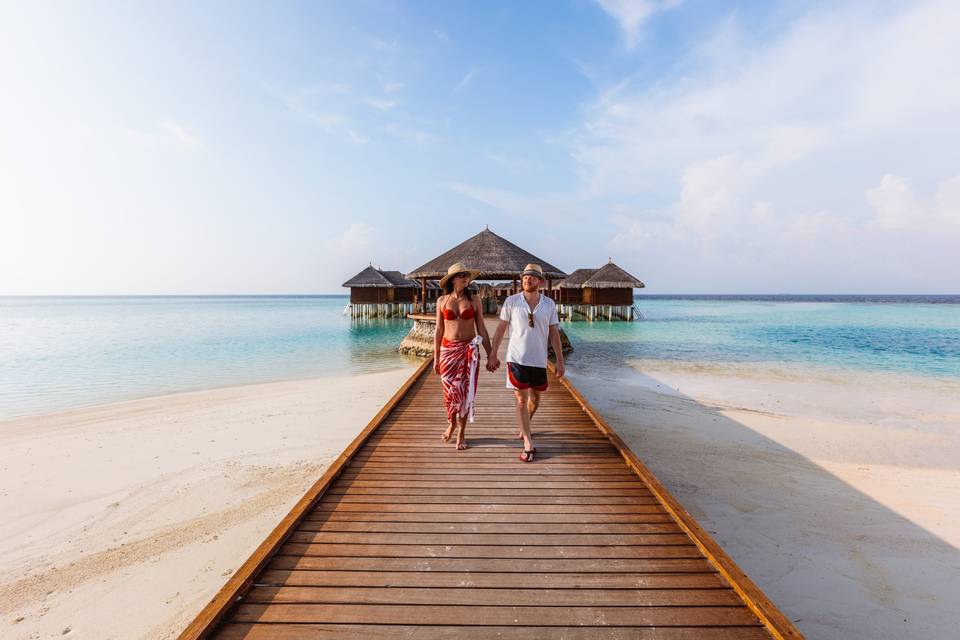 couple walking on dock in maldives