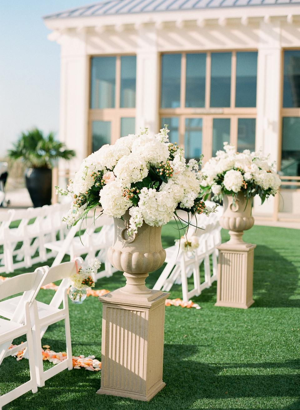 classic outdoor wedding aisle idea white hydrangea flower arrangements in stone urns on top of pillars