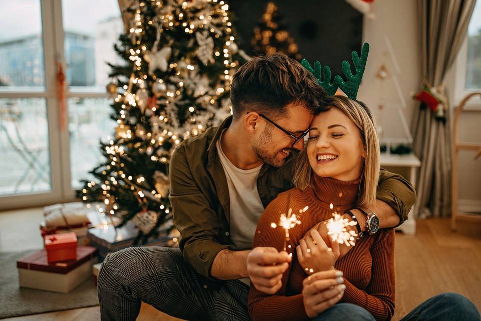 couple cuddling next to christmas tree