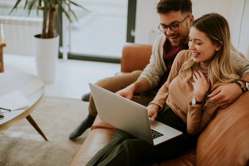 couple looking at laptop computer while sitting on a couch