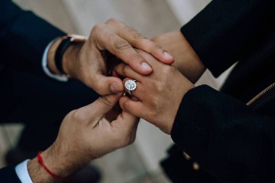 man placing engagement ring on woman's finger