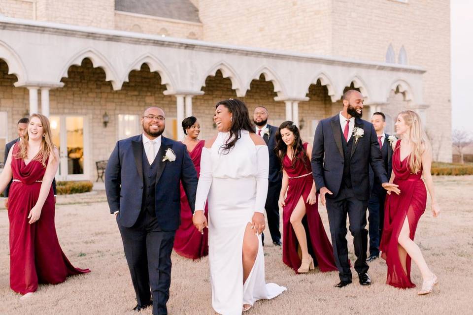 bride and groom laugh as they walk outdoors with their wedding party