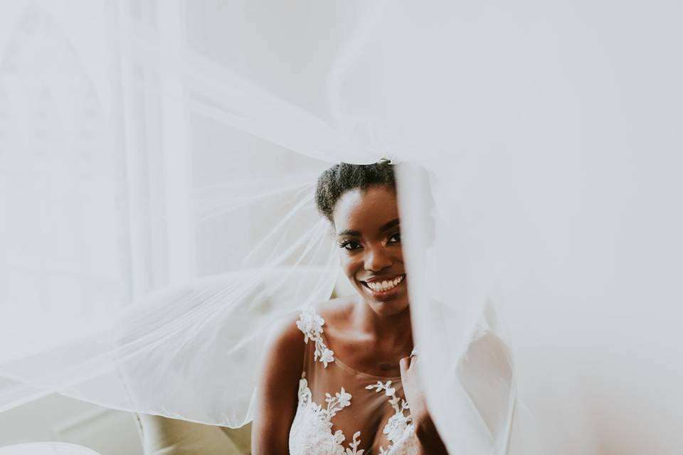 portrait of Black bride wearing veil smiling for the camera