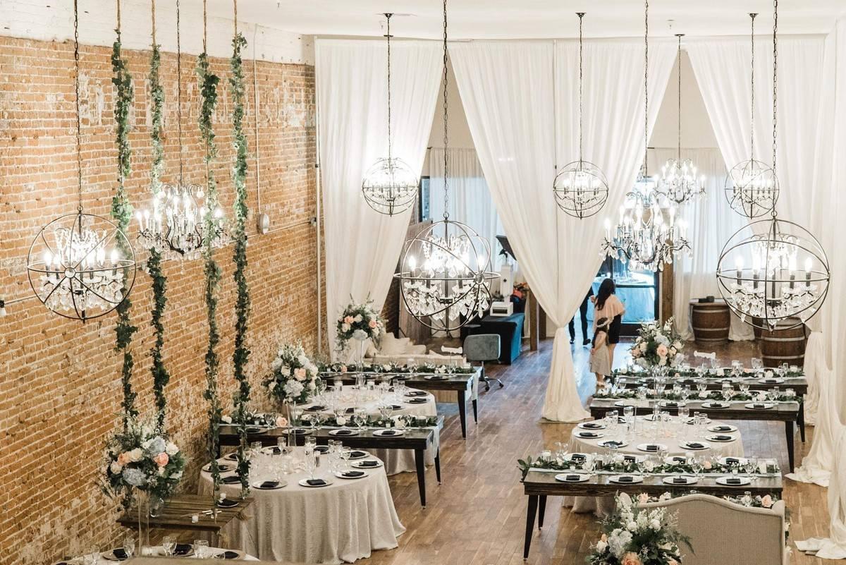 indoor wedding reception in industrial space with brick walls and spherical hanging light fixtures