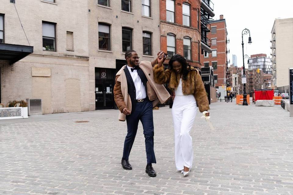 Black couple walking through New York City smiling laughing holding hands groom is twirling bride
