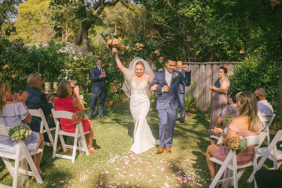 bride and groom celebrate walking down the aisle after backyard wedding ceremony