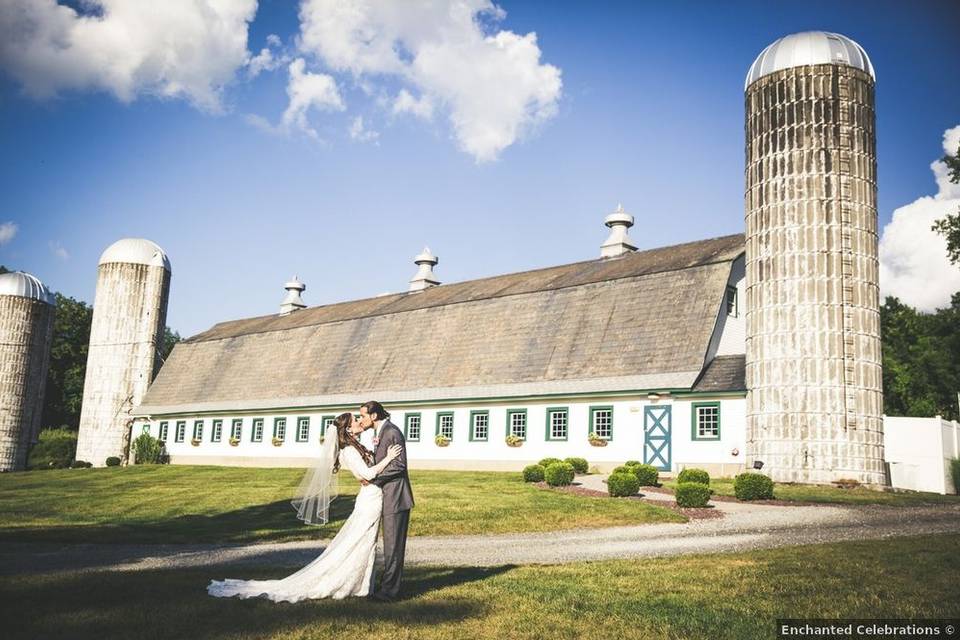 bride and groom kissing outside barn