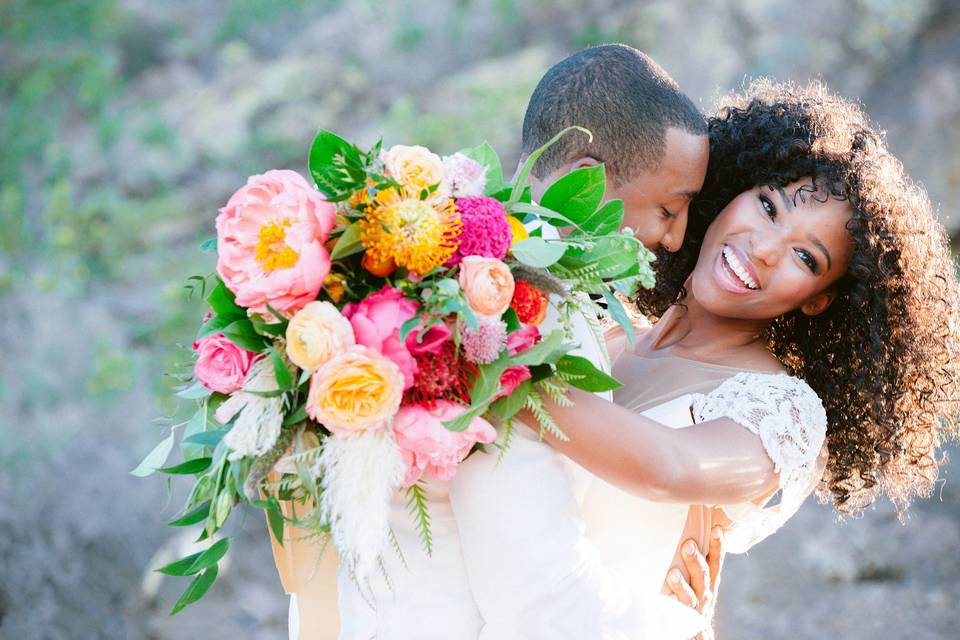 groom hugging bride, who is carrying a colorful bouquet