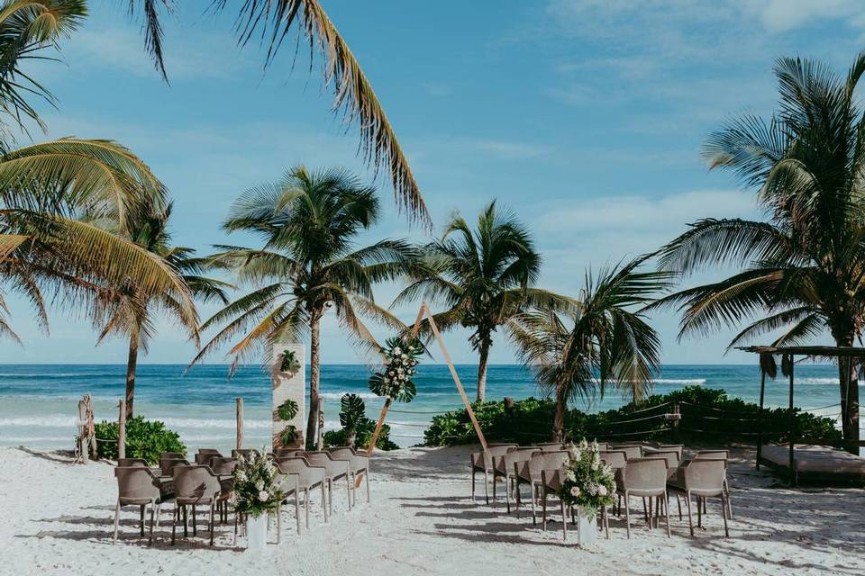 mexico beach wedding ceremony with triangle ceremony arch palm trees