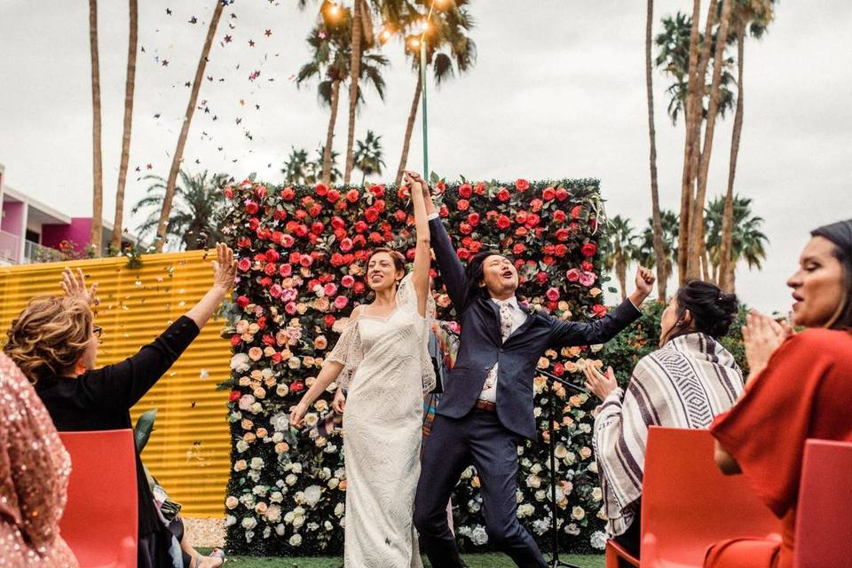 couple celebrating after wedding ceremony with colorful floral backdrop