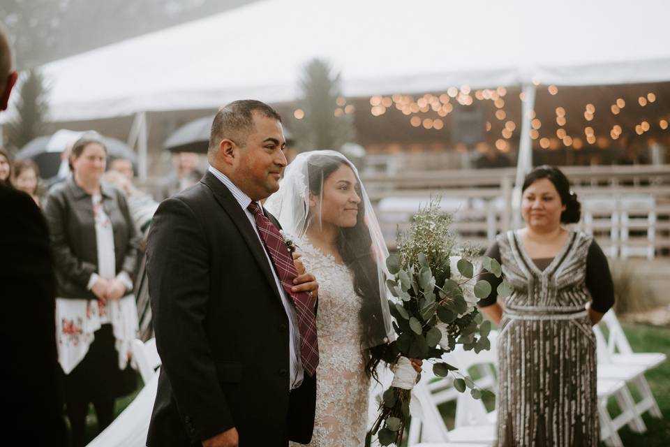 latina bride wearing a veil is escorted down the aisle by her father