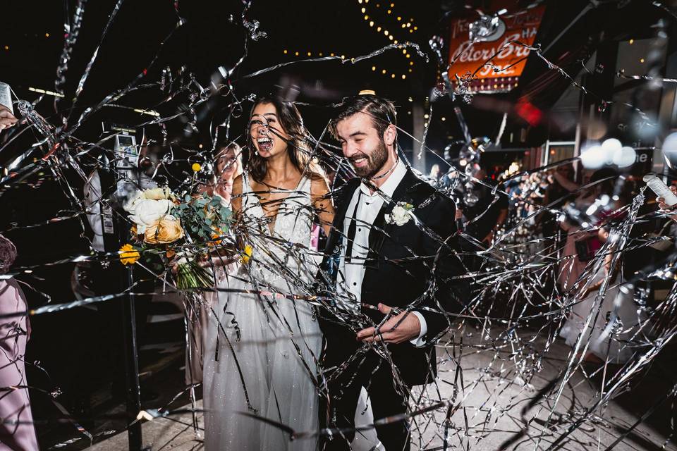 bride and groom amid silver streamers sendoff