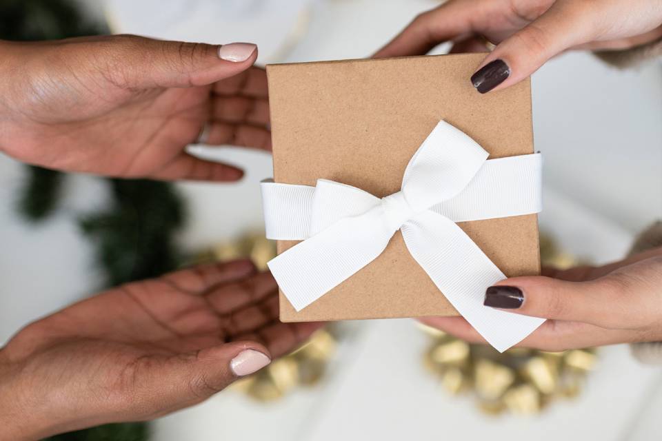 Hands exchanging a gift wrapped in a white bow