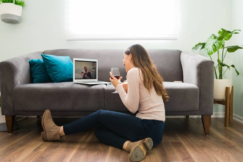 woman talking to man on a computer while drinking wine