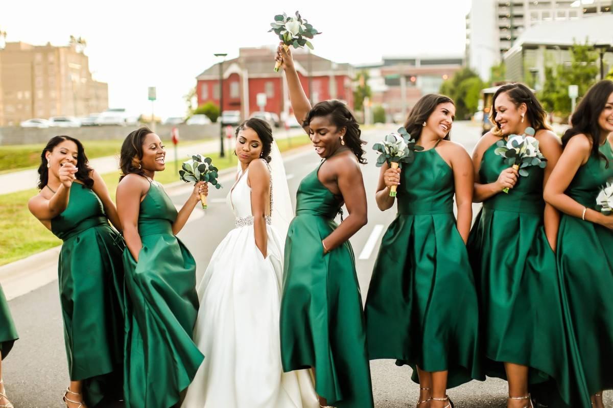 Bride and bridesmaids smiling and laughing together with wedding gown and green bridesmaid dresses