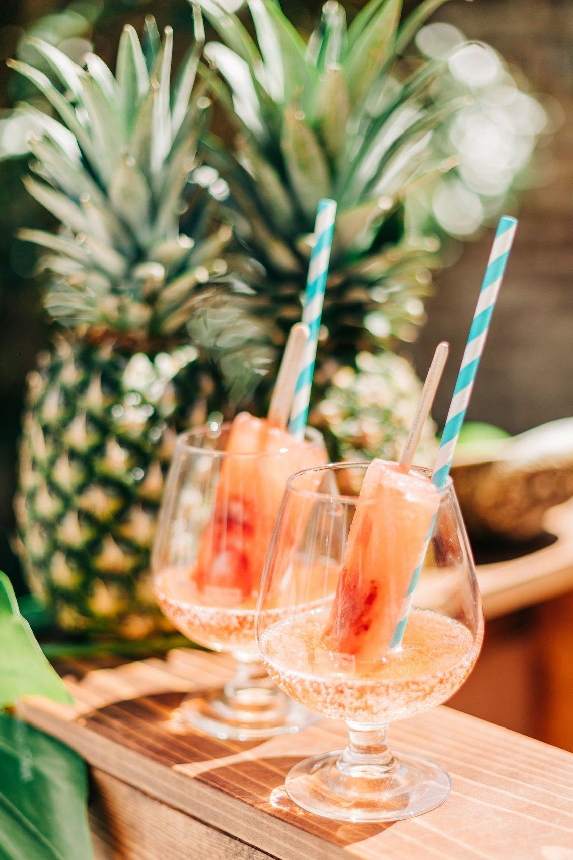 glasses with fruit popsicles in sparkling wine and turquoise paper straws